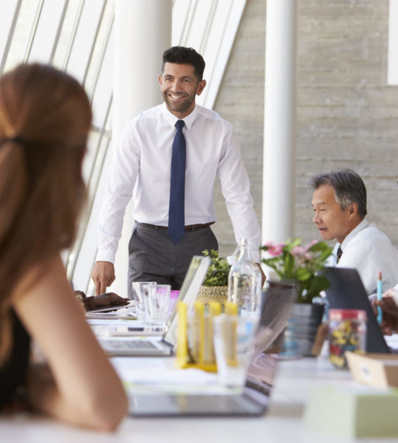 Hispanic Businessman Leading Meeting At Boardroom Table